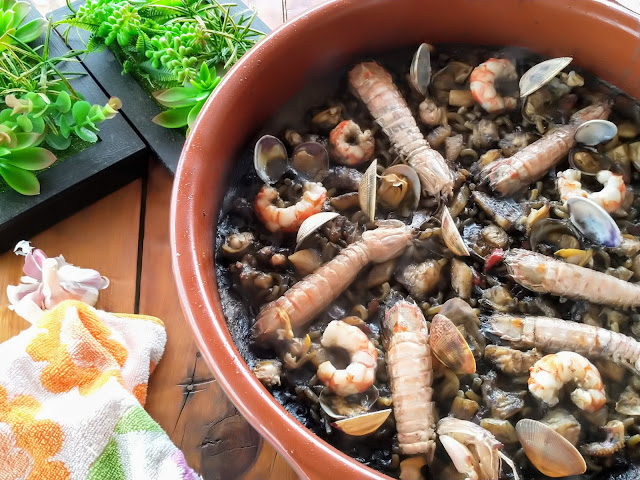 Fideuá de marisco negra en cazuela de barro