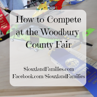 in background, a lime green lego helicopter has a blue ribbon tied to it from the Woodbury County Fair. In the foregrounds, the words "how to compete at the Woodbury County Fair"