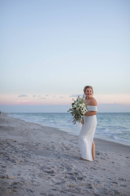 Bride walking down tropical outdoor setting with floral bouquet.