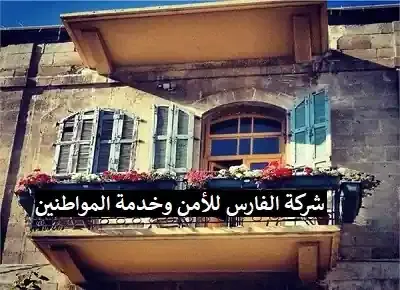 لافتة معلقة على شرفة منزل مكتوب عليها: شركة الفارس للأمن وخدمة المواطنين