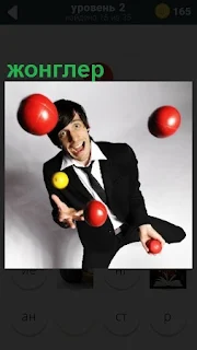 Мужчина жонглер играет шариками разного цвета, подбрасывая их вверх