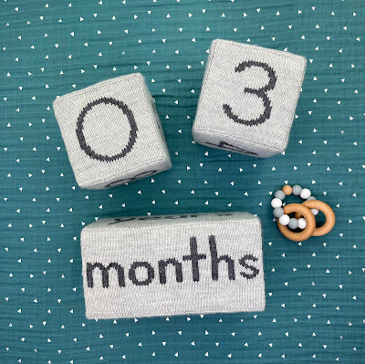 knitted gray milestone blocks on baby blanket showing 03 months