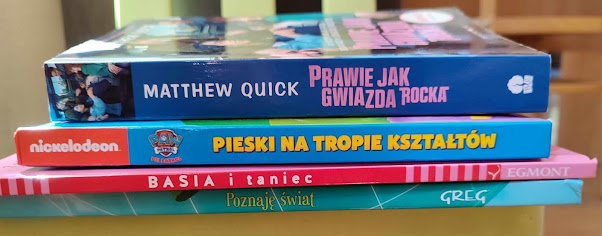 Na zdjęciu widnieje stos książek. Kolejno od góry: Matthew Quick. Prawie jak gwiazda rocka. Pieski na tropie kształtów. Basia i taniec. Egmont. Poznaję świat. Greg.