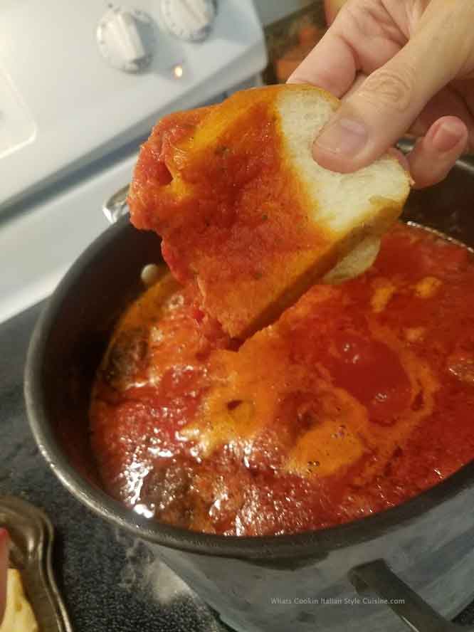 this is a pot of sauce and Italian bread dipping into it for a taste