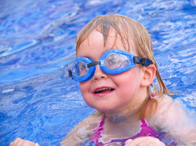 Happy little girl in swimming by the side of the pool.