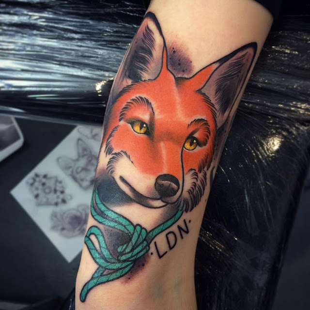 Arm tattoo of an orange fox head with an green rope tied around the neck