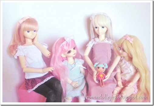 A msd sized ball jointed doll holding a lalaloopsy doll while two smaller yosd sized ball jointed dolls are looking at it and asking to play with it.  Now a second msd bjd is asking too.