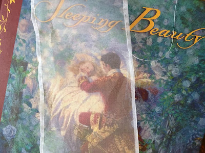 A narrow panel of white organza overlaid on a luminously illustrated picture book of Sleeping Beauty, with a partially stitched narrow hem on the right.