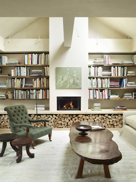 basement library with firewood stacked underneath wall of bookshelves, live edge coffee table
