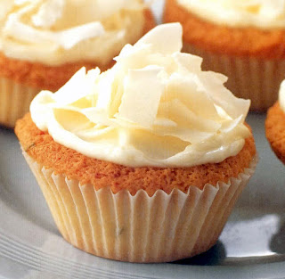 Creamy coconut cupcakes. White cupcakes with a cream cheese frosting and coconut shaving garnish.