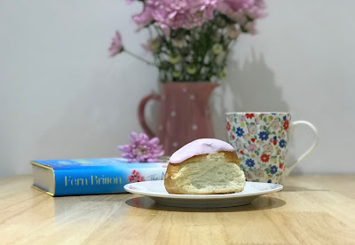 iced bun with a book, flowers and a mug in the background