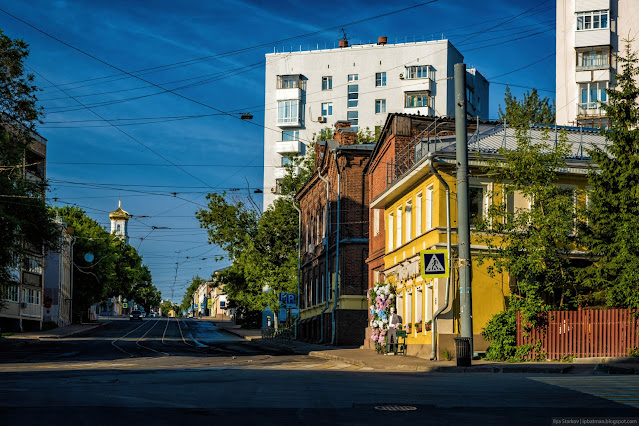 Городская улица с домами по бокам и церковью на фоне