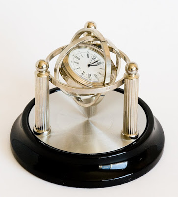 small desk clock on a black base with silver posts and swinging arms