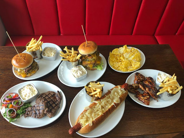 Six plates of food on a table at Richie's American Diner in Dartford, including nachos, steak, hot dogs and burgers