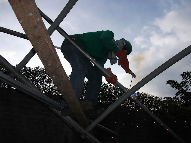 Welder tuck welding a pipe roof purlin