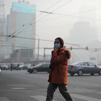 A woman wearing a face mask makes her way along a street in Beijing on January 16, 2014.