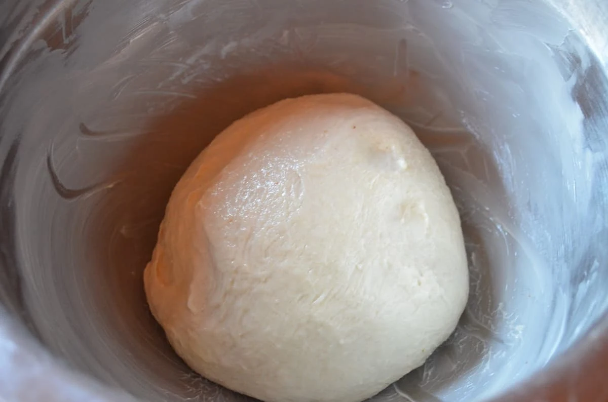 French Bread Dinner Rolls Dough in a buttered stainless steel bowl.