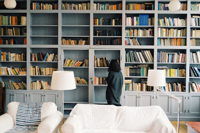 Woman organizing and showcasing book collections in a large home library.