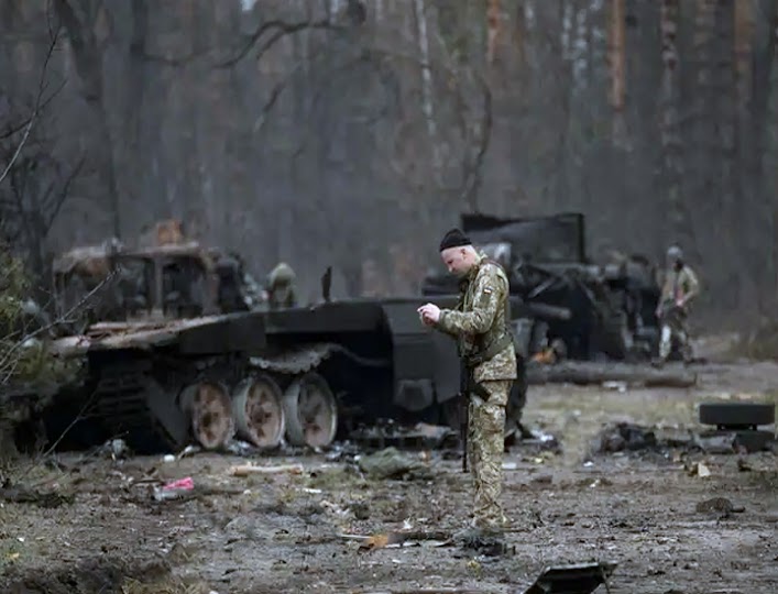 After Ukrainian forces overran a Russian stronghold outside Kyiv, Ukraine, on Thursday, March 31, 2022, a Ukrainian serviceman snaps a photo of a dead Russian soldier.