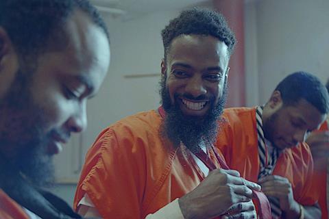 Black men teach each other how to tie a tie