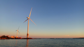 Kaksi tuulivoimalaa satamassa iltaruskossa