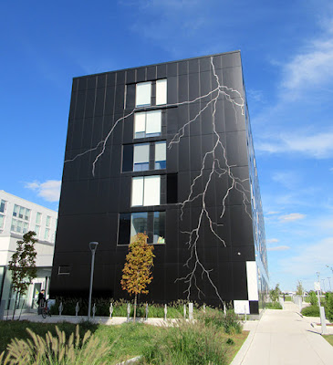 Etched art in the form of lightning running down the side of a black building, on a bright sunny, blue sky day