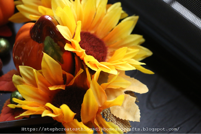 Close up of faux sunflowers, and orange pumpkin figurine