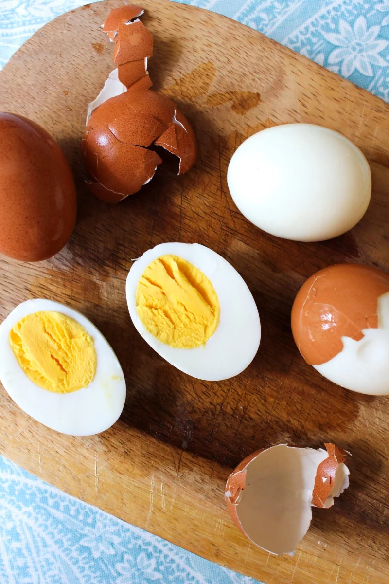 A cooked hard boiled egg cut in half on a wood cutting board.