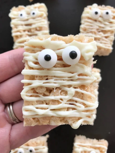 Close-up of a mummy crispy rice treat in a hand.