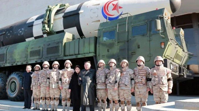 North Korean leader Kim Jong Un (center) and his daughter pose with soldiers for a photo in front of the Hwasong-17 intercontinental ballistic missile, at an unidentified location in North Korea.