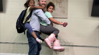 Dad carrying his daughters while they carry stuff