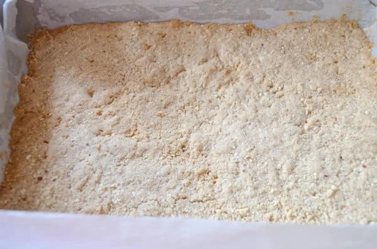 Baked Shortbread Almond Crust in a 9x13 metal baking pan lined with parchment paper.