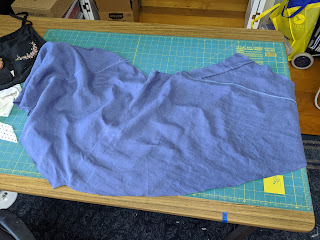 a blue piece of fabric lays on the cutting table, abandoned and desolate
