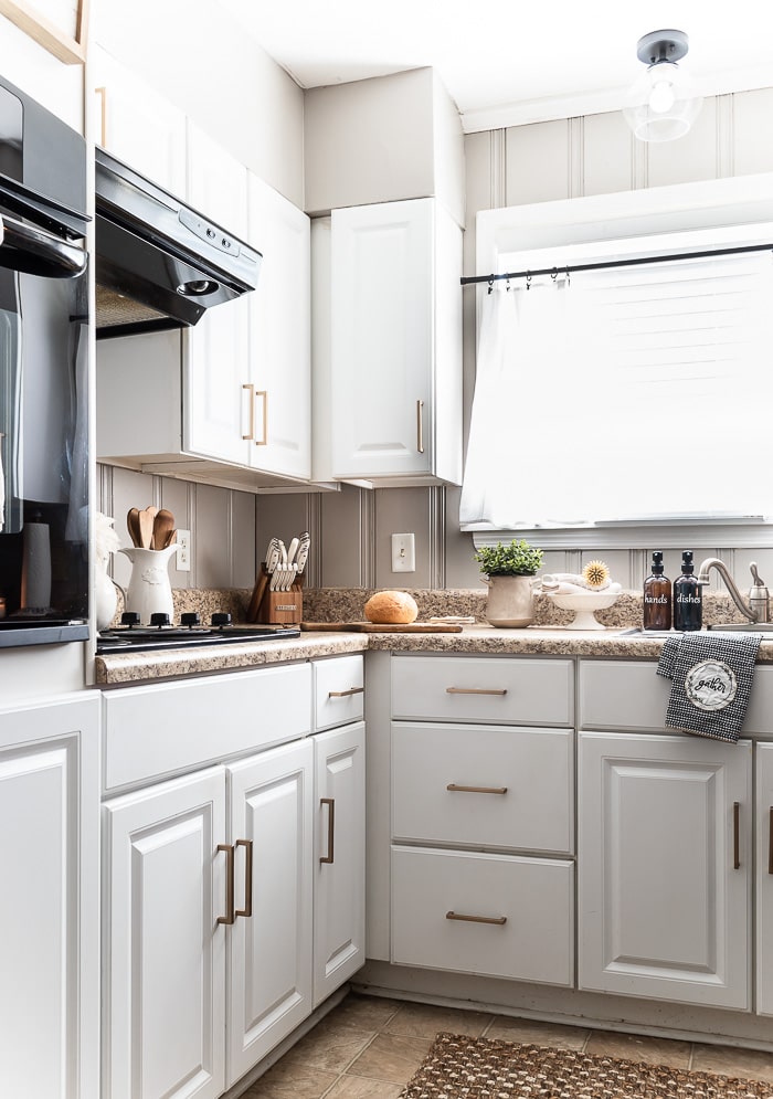 white kitchen, modern bronze pulls, black appliances
