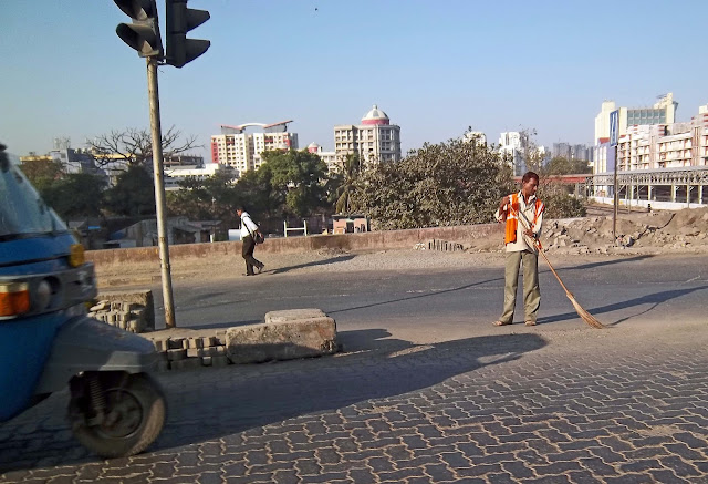 municipal worker sweeping road in reflective jacket