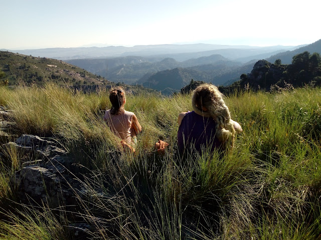 2 hikers sit in the high grass and watch a great view over the mountains
