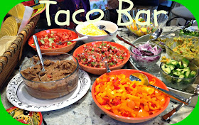 taco bar with bowls of vegetables, refried beans, bean, and salsa