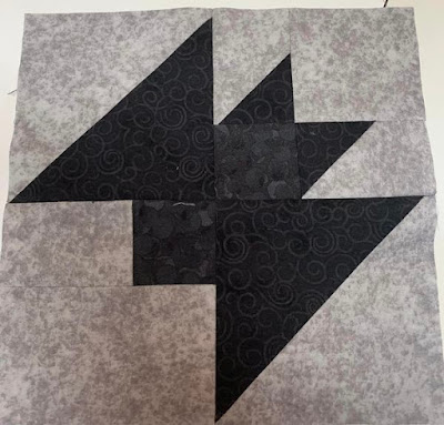 A quilt block of a black bat on grey background