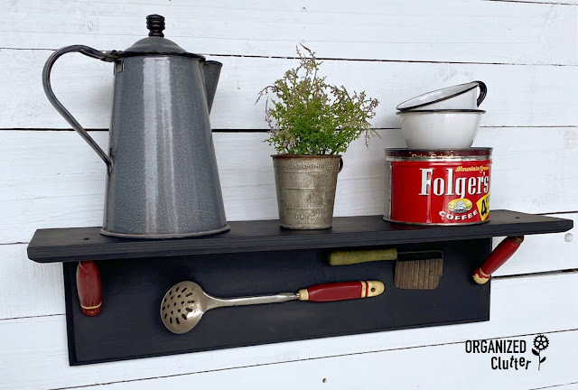 Photo of a farmhouse kitchen shelf with attached faux utensils.