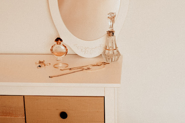 A bedroom counter top with perfumes and jewelry displayed.