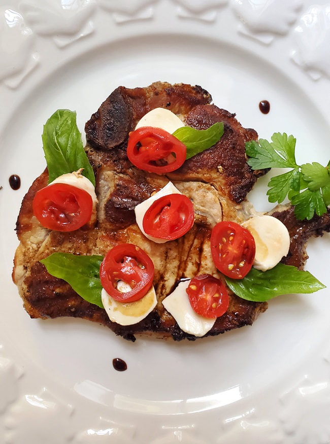 pork chops topped with a tomato and mozzarella salad drizzled with balsamic vinegar