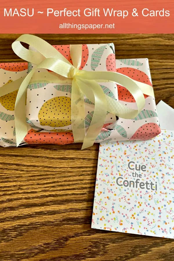 two gifts wrapped in dotted wrapping paper decorated with citrus fruits, tied with yellow ribbon and pictured alongside dotted, colorful greeting card with Cue the Confetti sentiment