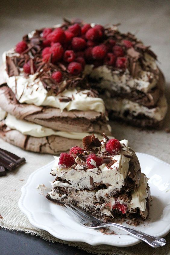 A rich chocolate meringue layer cake. Chocolate meringue, layered with vanilla bean whipped cream, topped with raspberries and chocolate shavings.