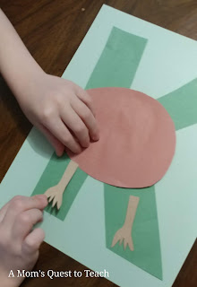 gluing legs of construction paper kiwi onto letter K with glue stick