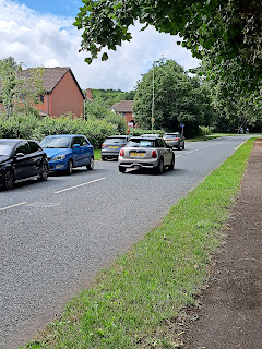 Photo of parked cars with passing care forced onto wrong side of road just before a bend