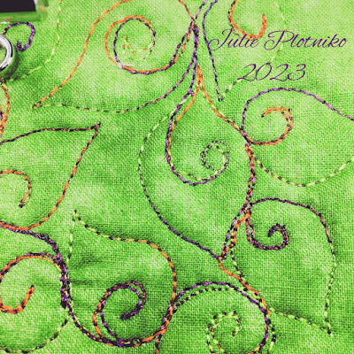 A FMQ desing of curling leaves on bright green fabric