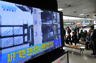 Người dân Hàn Quốc theo dõi vụ phóng vệ tinh của CHDCND Triều Tiên qua màn hình tivi ở một nhà ga tại Seoul vào ngày 13.4