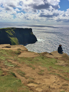 Sitting on the edge of the Cliffs of Moher, County Clare, Ireland