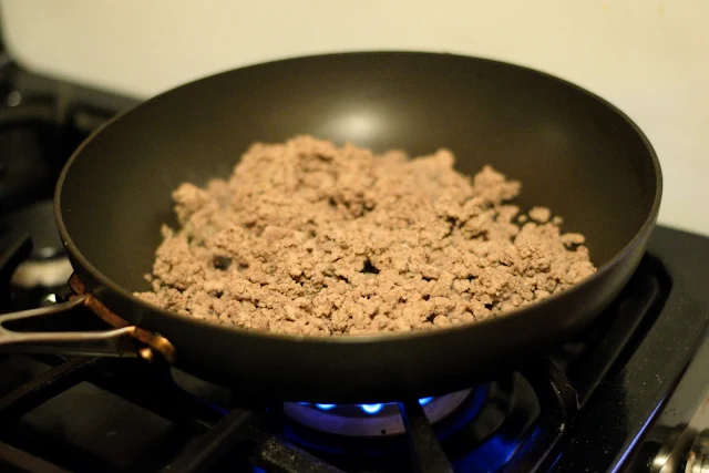 Ground beef in the pan on the stove.