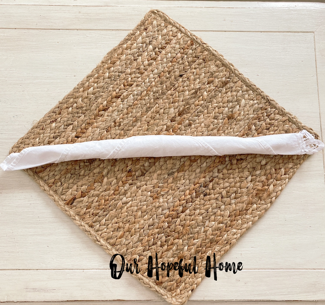 white rolled up napkin on jute placemat